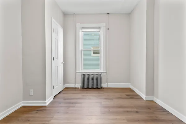 a view of an empty room with wooden floor and a window