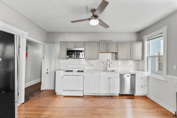 a large white kitchen with stainless steel appliances granite countertop a stove a sink and a refrigerator