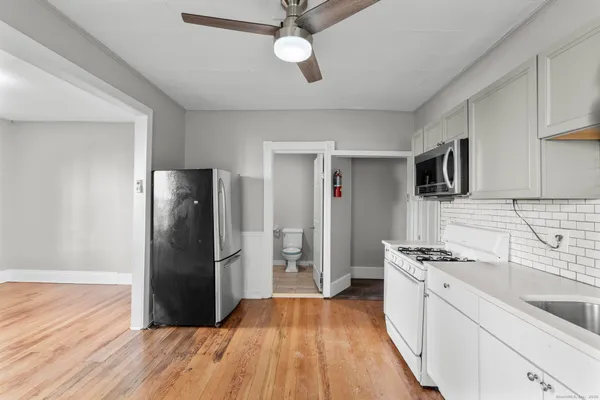a kitchen with stainless steel appliances granite countertop a refrigerator a stove and a sink with wooden floor