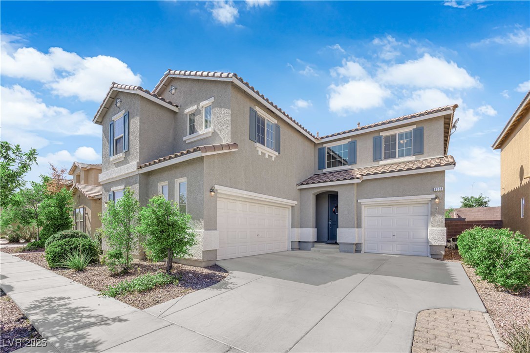 Mediterranean / spanish-style house featuring an attached garage, stucco siding, a tile roof, and concrete driveway