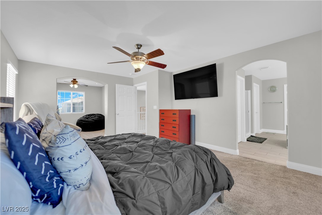 9005 Rendon Street Las Vegas, NV 89143 - Photo 20 of 51 Bedroom featuring arched walkways, light carpet, a ceiling fan, and ensuite bath
