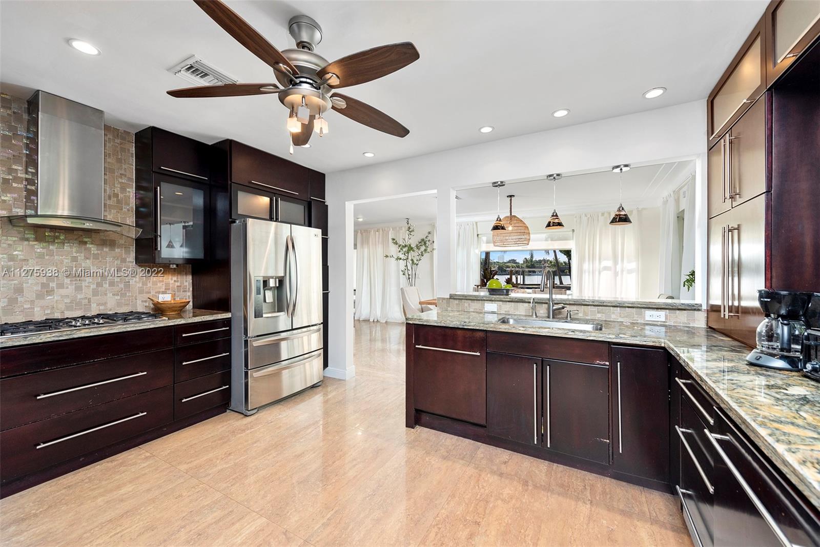 940 88th Street Surfside, FL 33154 - Photo 20 of 38 a large kitchen with stainless steel appliances kitchen island granite countertop a refrigerator and a sink