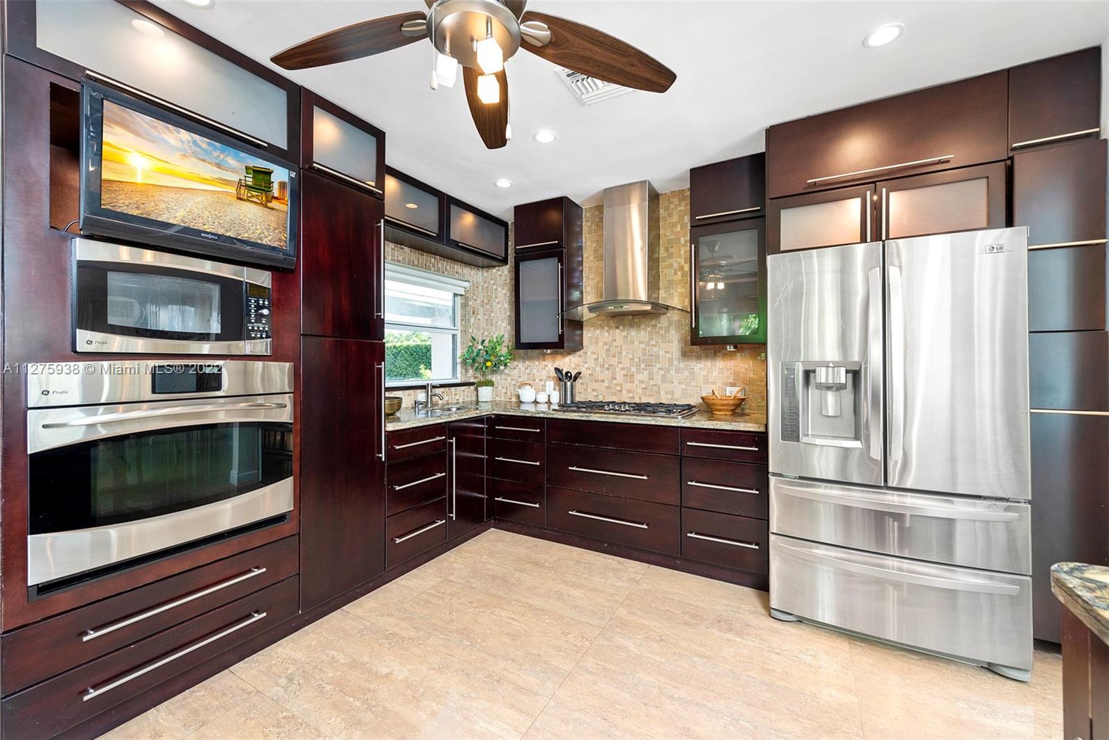 940 88th Street Surfside, FL 33154 - Photo 21 of 38 a kitchen with stainless steel appliances kitchen island granite countertop a refrigerator and a stove top oven