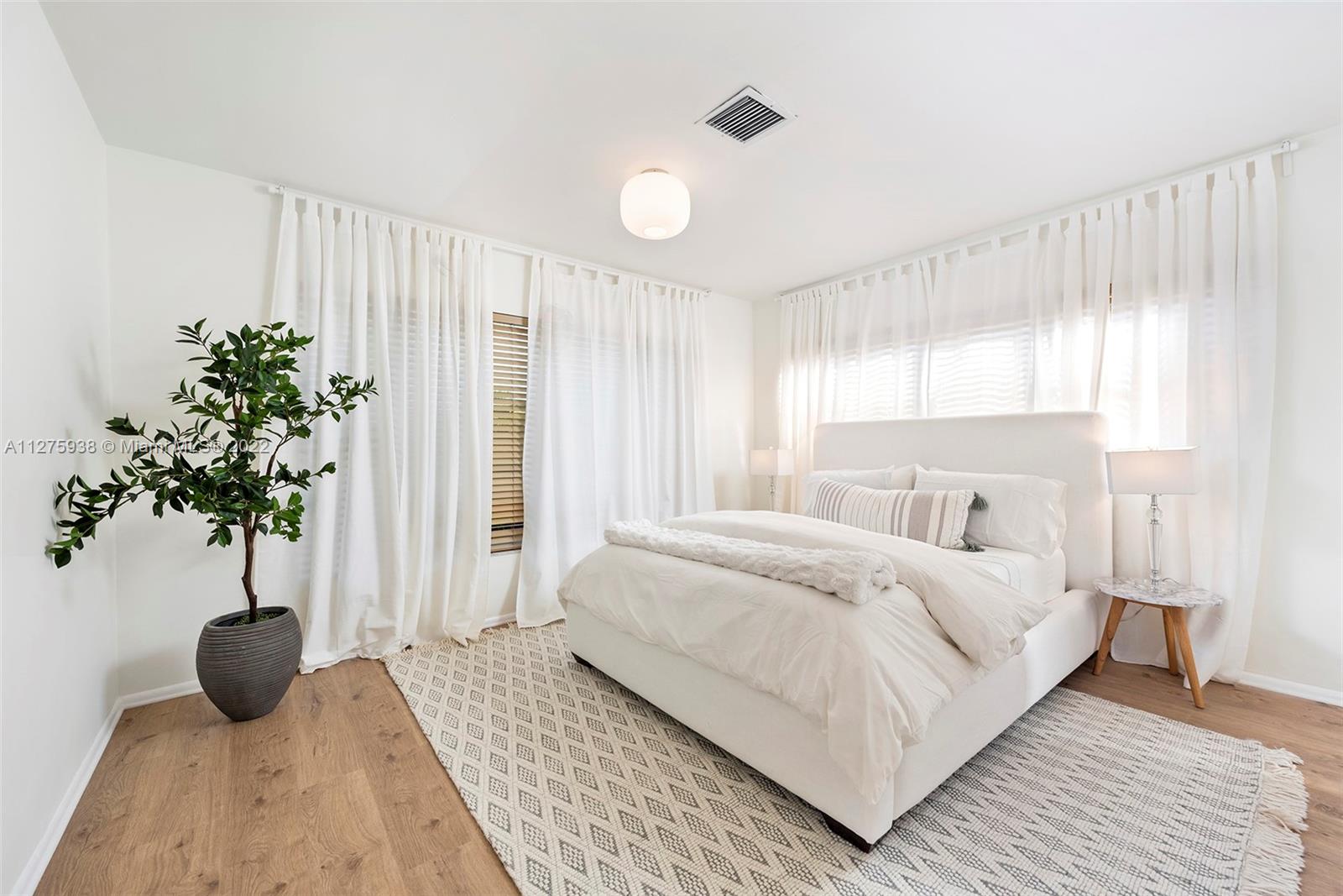 940 88th Street Surfside, FL 33154 - Photo 33 of 38 a bedroom with a large bed and a potted plant