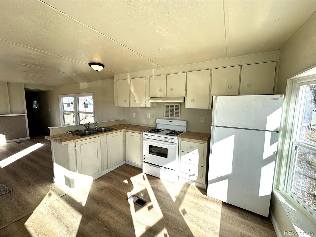 155 Indiana Avenue Limon, CO 80828 - Photo 7 of 27 a kitchen with a refrigerator a stove a sink dishwasher and white cabinets with wooden floor