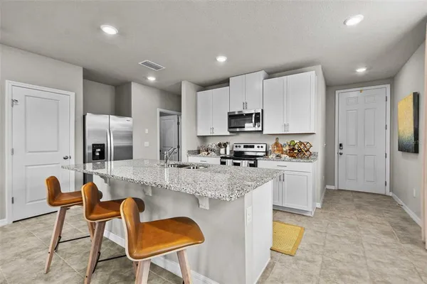 a kitchen with stainless steel appliances granite countertop a stove top oven a sink refrigerator and white cabinets