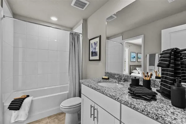 a bathroom with a granite countertop sink a toilet a mirror and shower