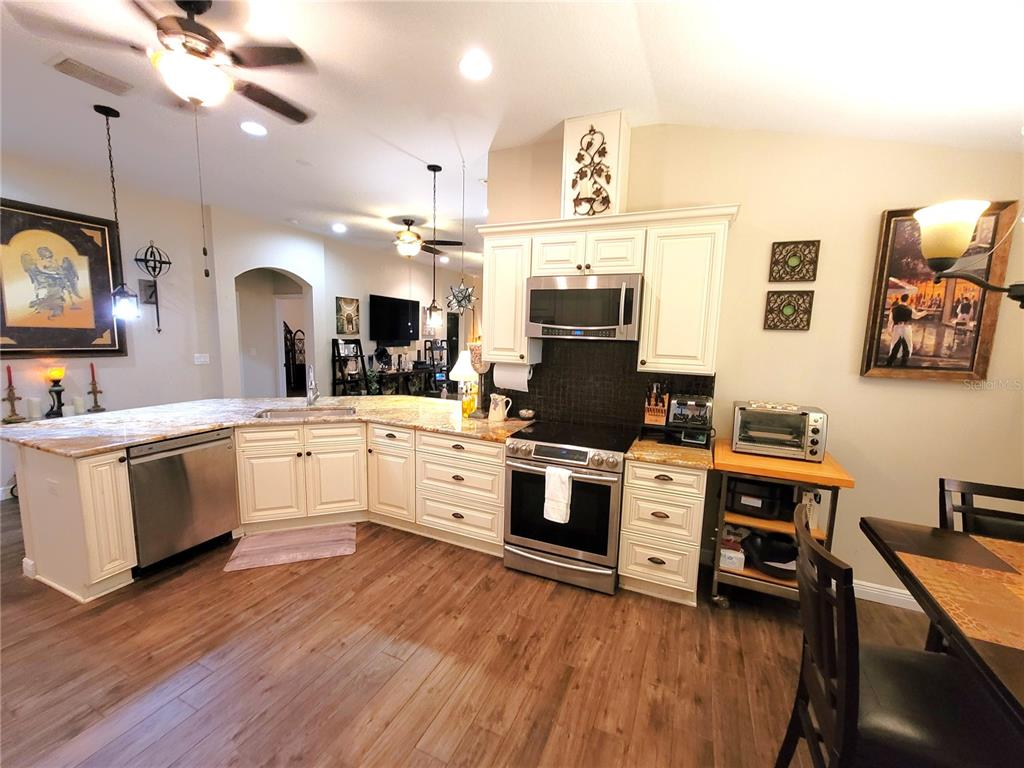 1001 Torreya Way Odessa, FL 33556 - Photo 12 of 44 a kitchen with stainless steel appliances white cabinets a sink a stove a refrigerator and island with wooden floor