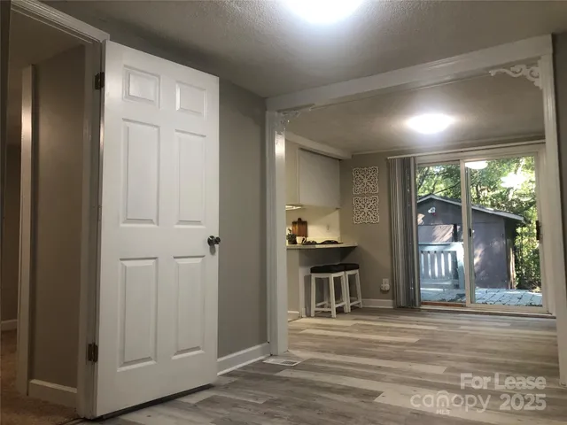 a view of a livingroom with wooden floor and a kitchen space