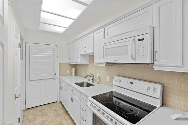 a kitchen with white cabinets and white appliances