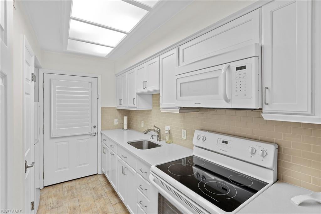 72 7th Street South, Unit 208 Naples, FL 34102 - Photo 9 of 21 a kitchen with white cabinets and white appliances