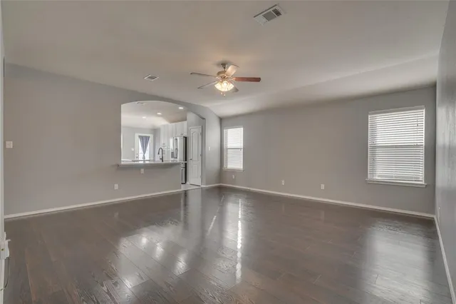 a view of an empty room with a window and wooden floor