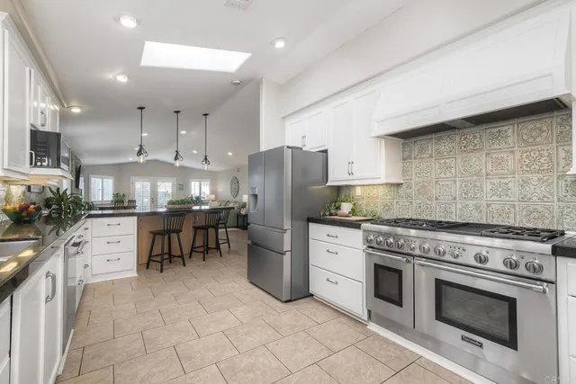 a kitchen with stainless steel appliances granite countertop a stove refrigerator and cabinets