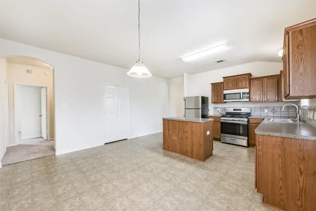 a kitchen with stainless steel appliances granite countertop a stove a sink a refrigerator and a refrigerator