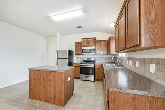 a kitchen with stainless steel appliances granite countertop wooden cabinets a stove top oven a sink and dishwasher