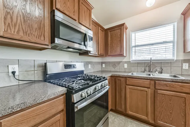 a kitchen with stainless steel appliances granite countertop a sink stove and microwave