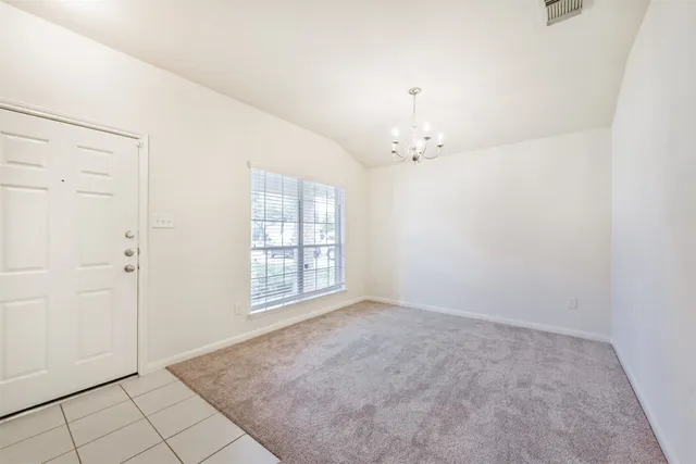 an empty room with chandelier fan and windows