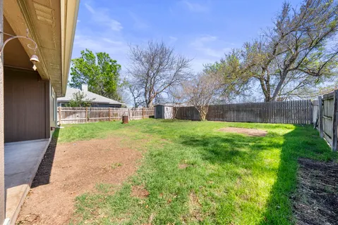 a view of backyard with wooden fence