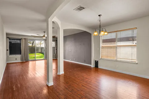 an empty room with wooden floor and chandelier