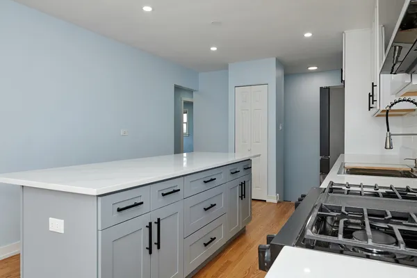 a kitchen with stainless steel appliances a stove and white cabinets