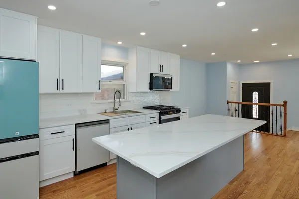 a large kitchen with kitchen island a sink a stove and a refrigerator
