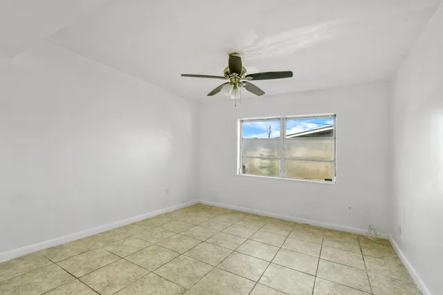 an empty room with a window and a fan