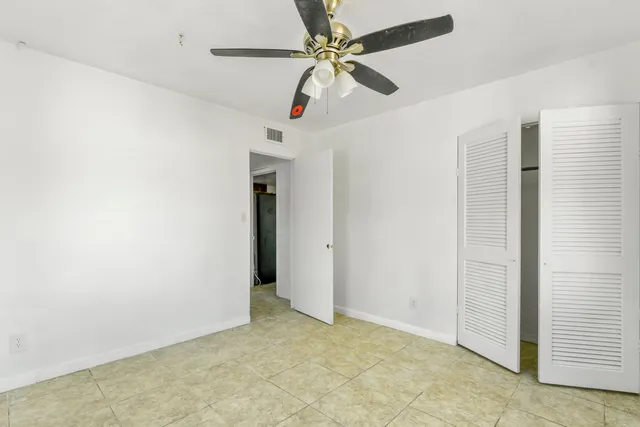 an empty room with ceiling fan and window