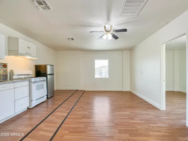 a view of an empty room with window cabinet a kitchen and a chandelier fan