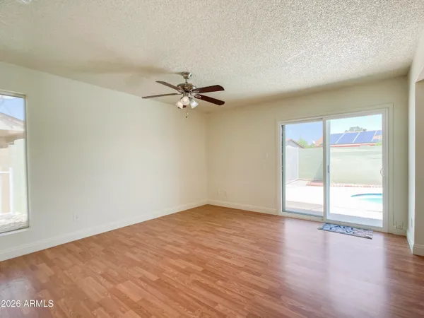 an empty room with wooden floor fan and windows