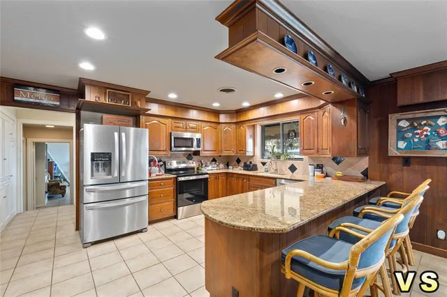 a kitchen with granite countertop a refrigerator a stove a sink and a dining table with wooden floor