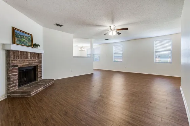 an empty room with wooden floor fireplace and fan