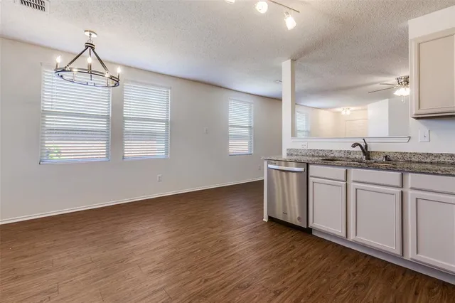 a kitchen with stainless steel appliances granite countertop a stove a sink and white cabinets with wooden floor