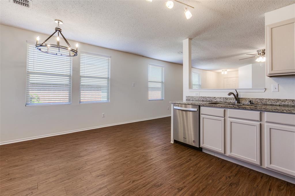 2613 Salt Maker Way Little Elm, TX 75068 - Photo 8 of 16 a kitchen with stainless steel appliances granite countertop a stove a sink and white cabinets with wooden floor