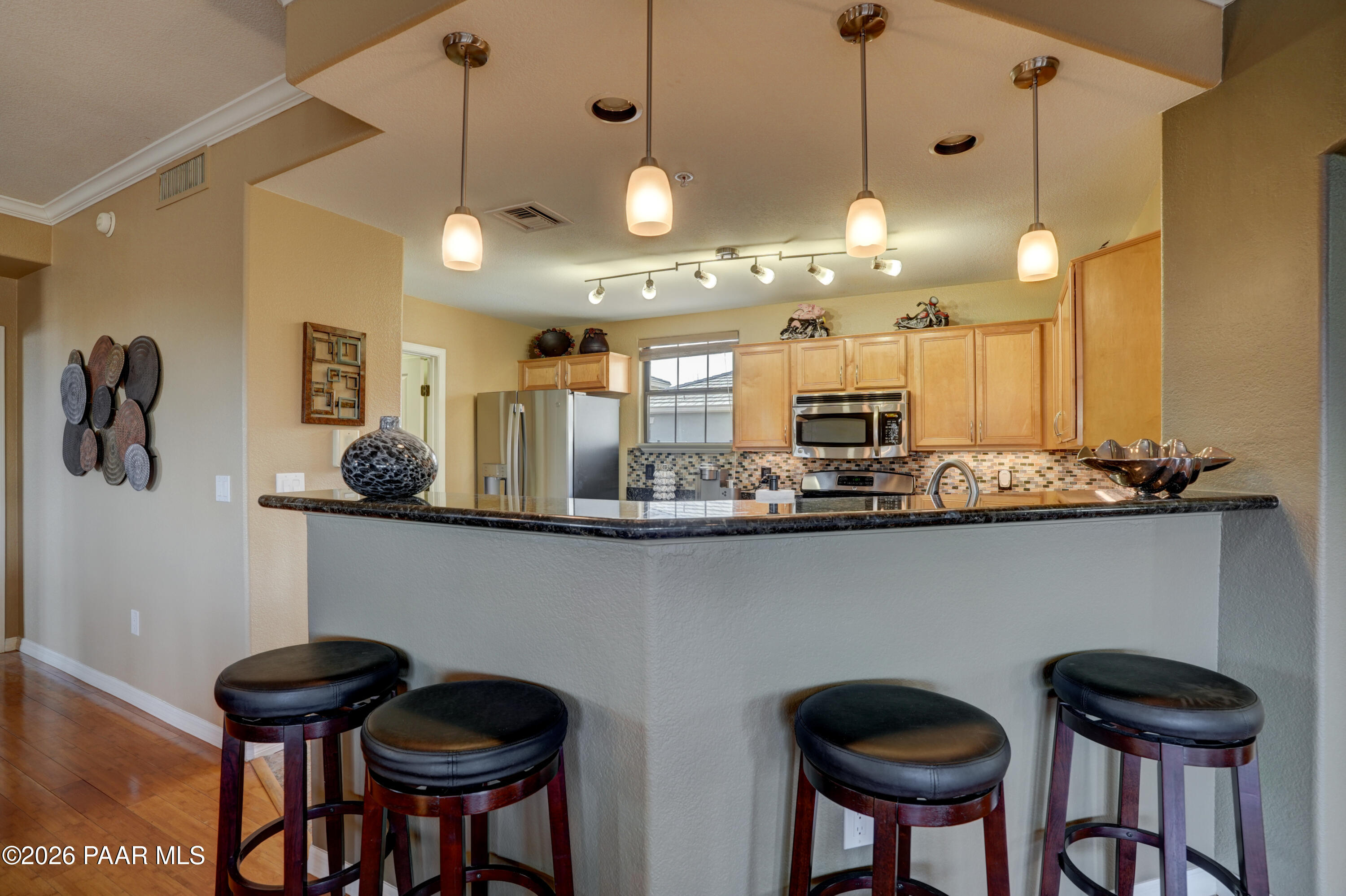 1716 Alpine Meadows Lane, Unit 405 Prescott, AZ 86303 - Photo 14 of 29 a kitchen with stainless steel appliances kitchen island granite countertop a table and chairs in it