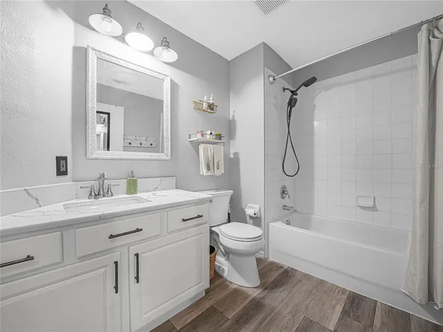 a bathroom with a granite countertop sink toilet a mirror and shower