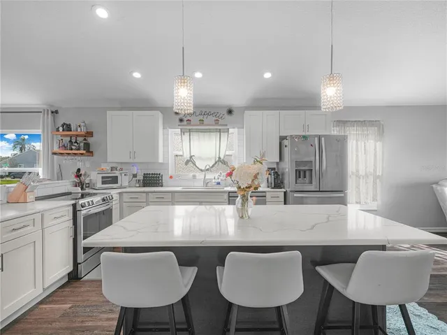 a large kitchen with kitchen island a dining table chairs sink and cabinets