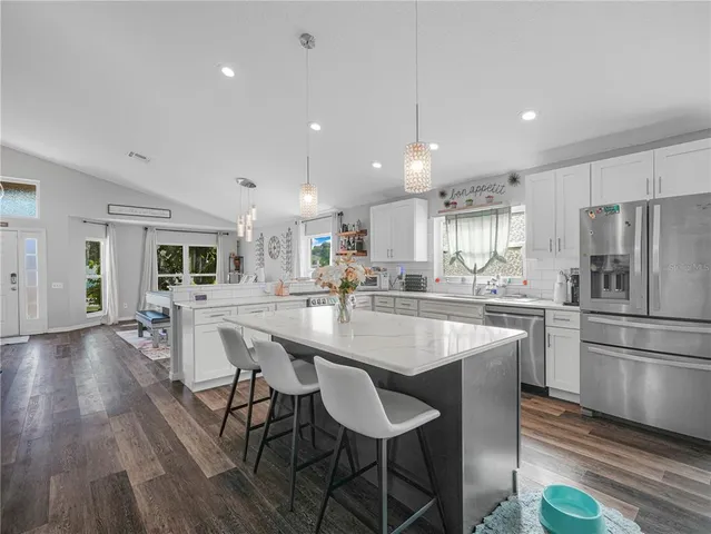 a kitchen with stainless steel appliances granite countertop a dining table chairs refrigerator sink and cabinets