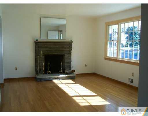 172 Normandy Road Colonia, NJ 07067 - Photo 4 of 5 a view of an empty room with wooden floor and a fireplace