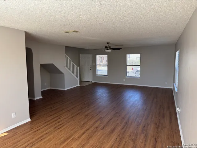 an empty room with wooden floor and windows