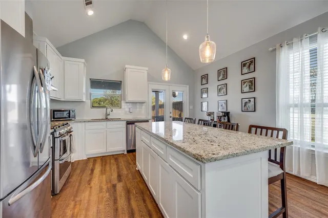 a large living room with stainless steel appliances granite countertop couches a fireplace and wooden floor