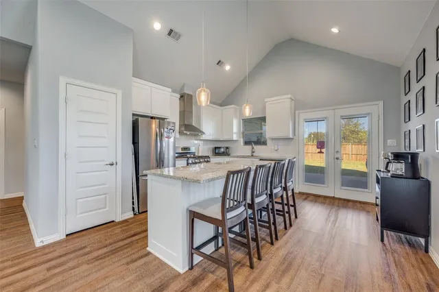 a kitchen with stainless steel appliances kitchen island granite countertop wooden floors and white cabinets