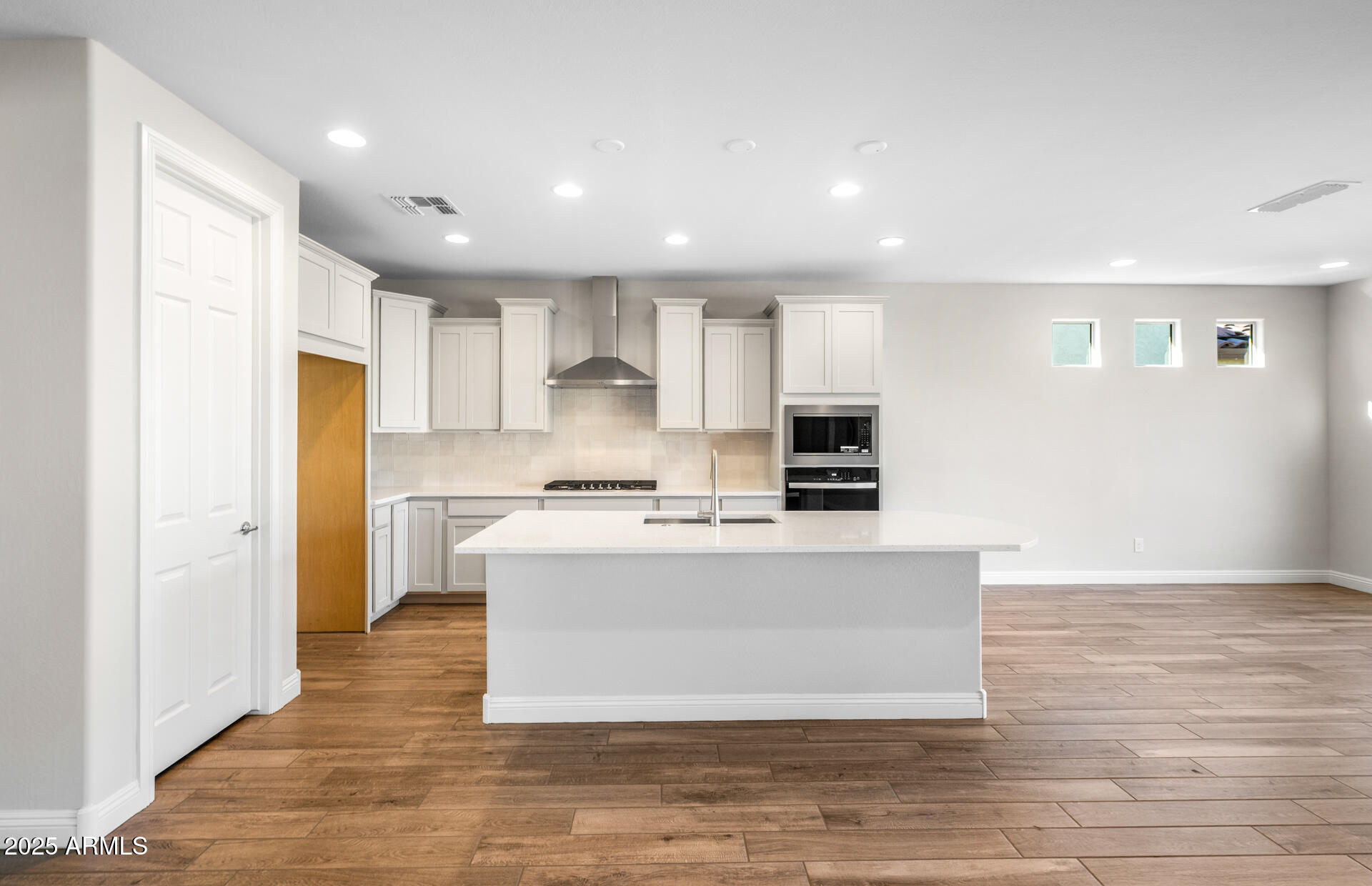 6808 West Ripken Way Florence, AZ 85132 - Photo 21 of 38 a large kitchen with kitchen island a sink a stove a refrigerator and white cabinets