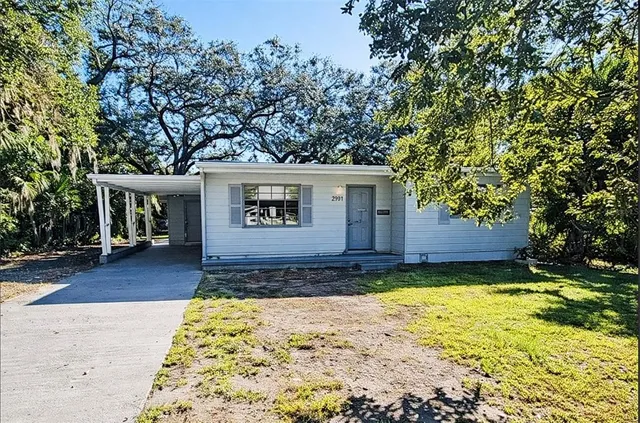 a front view of a house with a yard and a tree