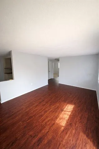 a view of a big room with wooden floor and windows