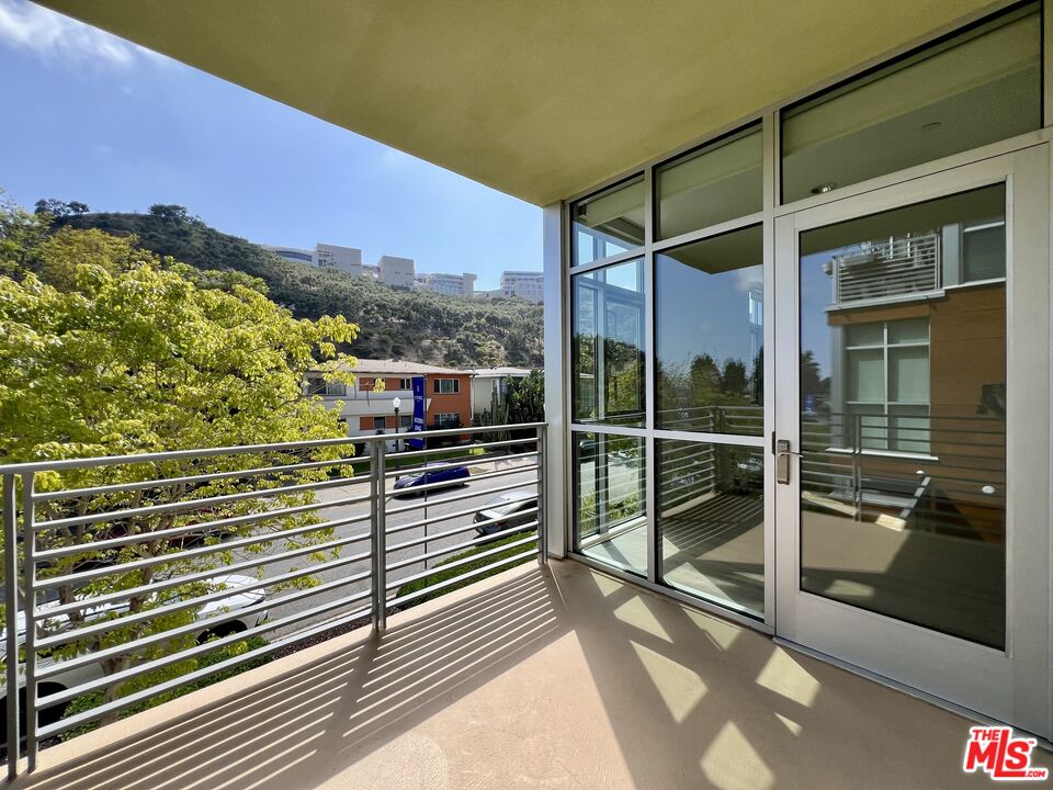 11715 Bellagio Road, Unit 204 Los Angeles, CA 90049 - Photo 18 of 27 a view of a balcony with a floor to ceiling window and wooden floor