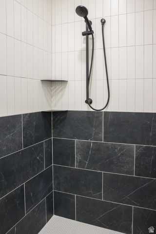 3322 250 S Street Vernal, UT 84078 - Photo 19 of 37 Shower featuring a matte black shower system with a handheld spray, white vertical subway tile, black patterned tile wainscoting, and a built-in corner shelf