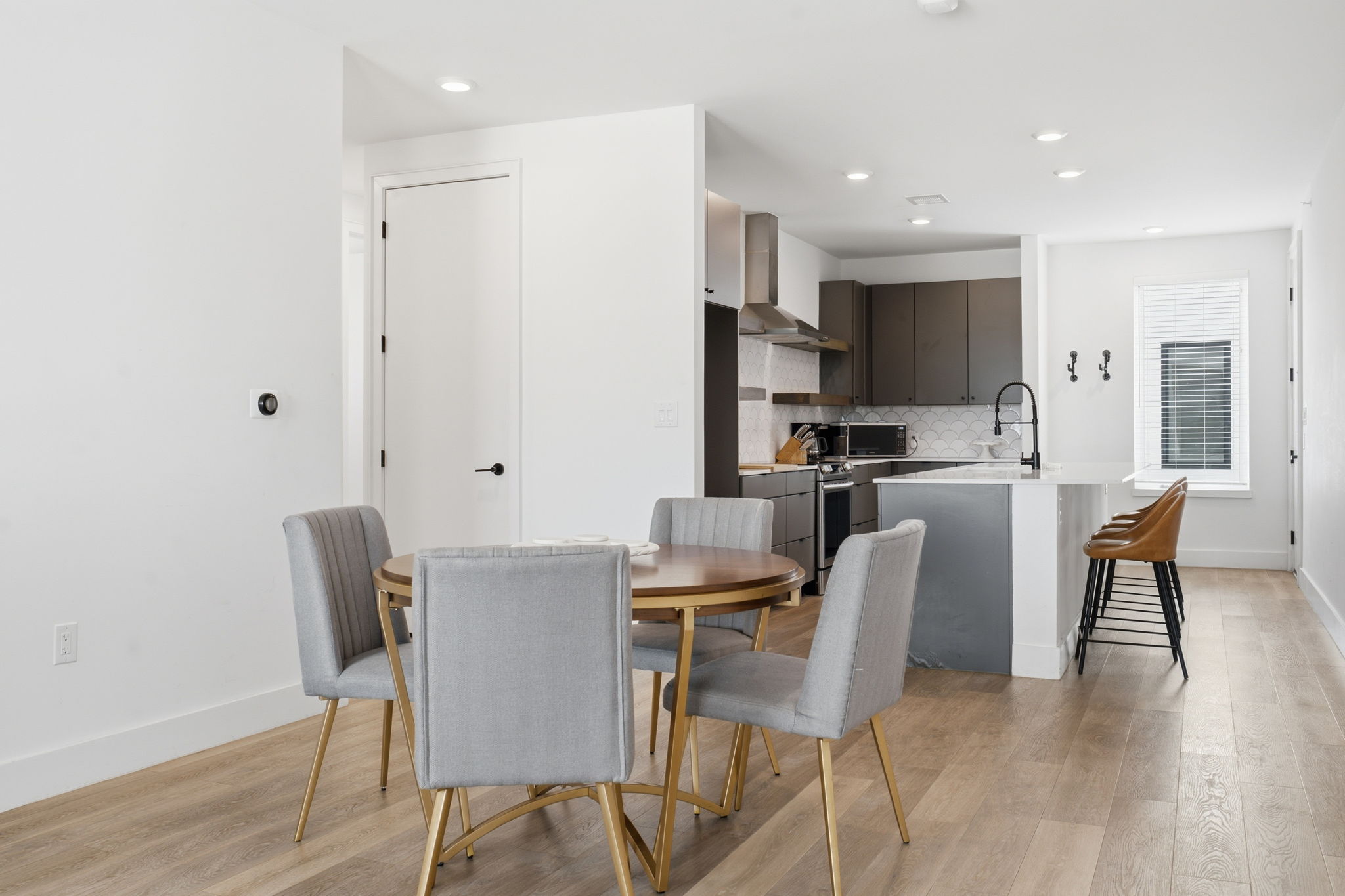 2709 East 5th Street, Unit 1306 Austin, TX 78702 - Photo 5 of 28 Blonde hardwood floors flow through an open-concept kitchen and dining area with a versatile island.