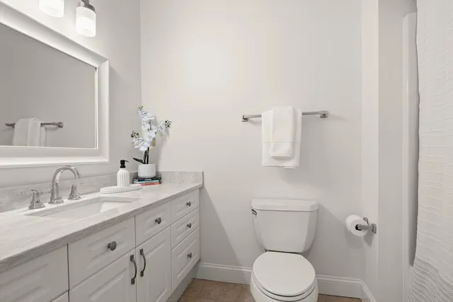 a bathroom with a granite countertop toilet sink and mirror