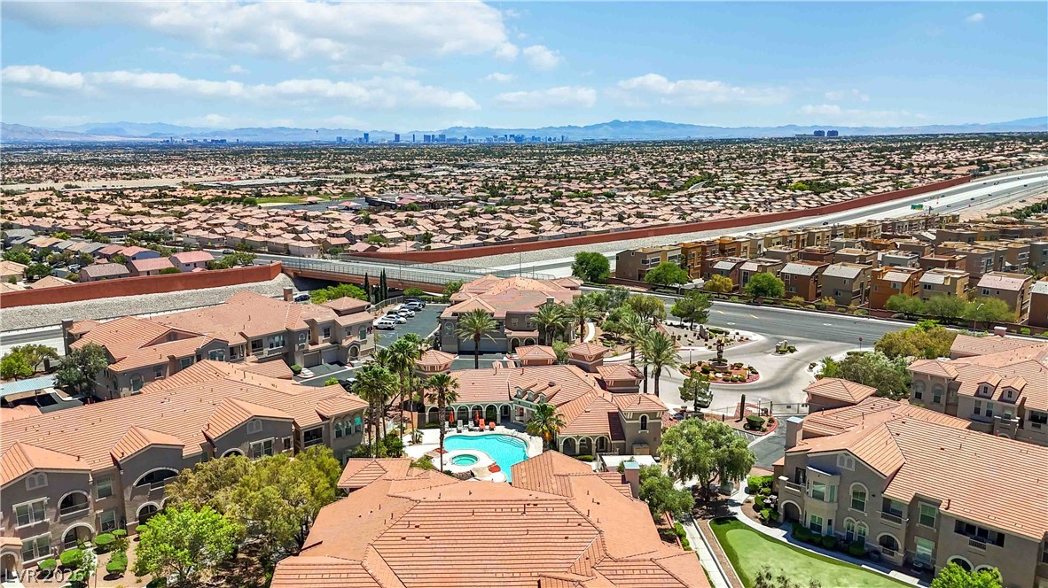 10550 West Alexander Road, Unit 2060 Las Vegas, NV 89129 - Photo 39 of 45 An aerial perspective reveals a vibrant community with inviting pool areas, framed by distant mountains and a metropolitan skyline.
