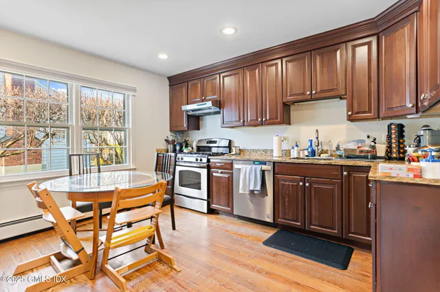 a kitchen with stainless steel appliances granite countertop wooden cabinets a dining table and chairs